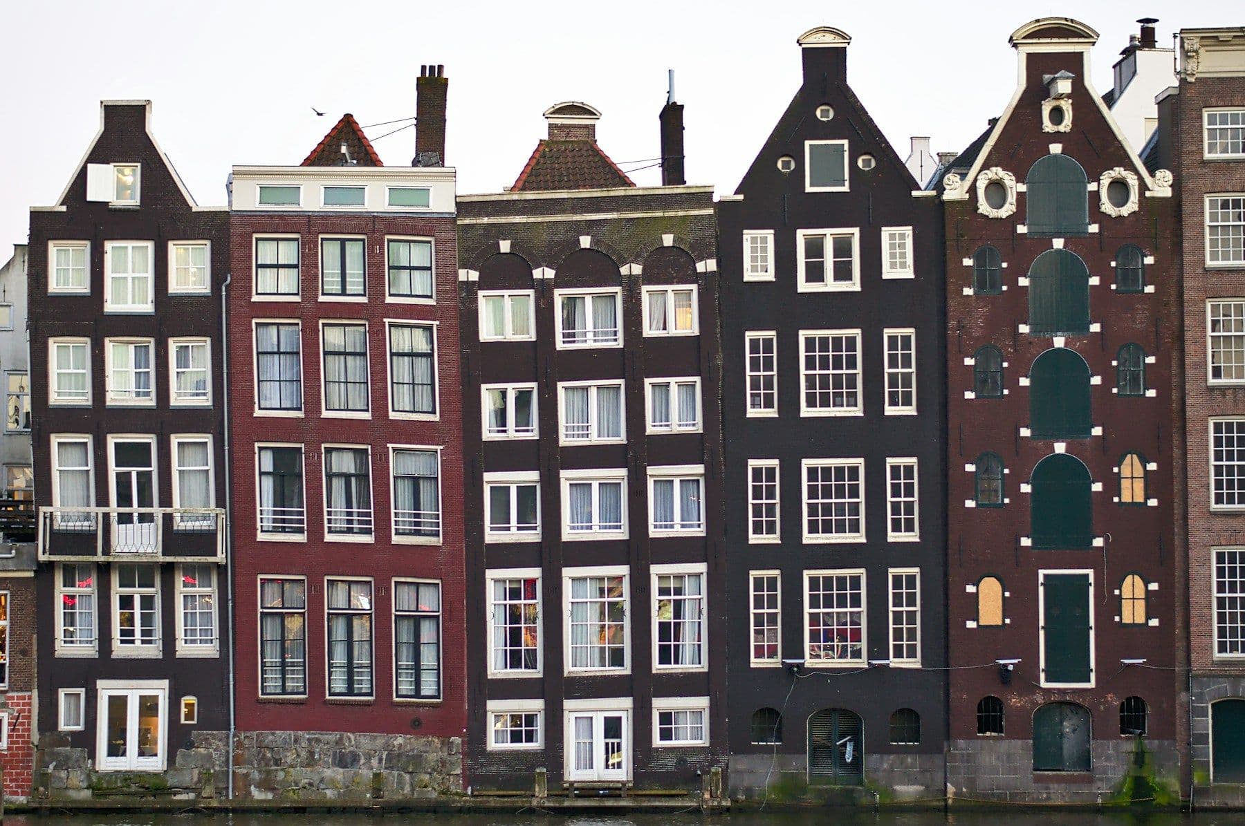 Rij smalle Amsterdamse grachtenpanden in donkere en rode baksteen